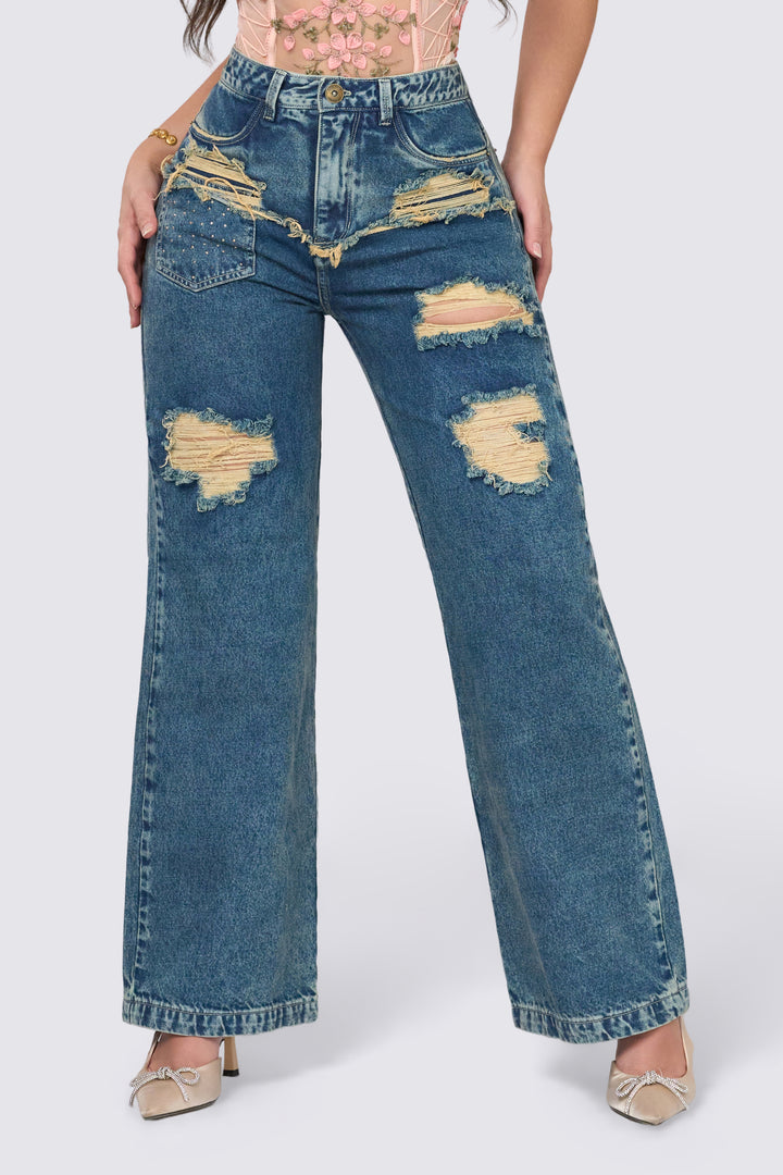 Wide-leg pants with a washed look, distressed detailing on the front, and metallic appliqués. 