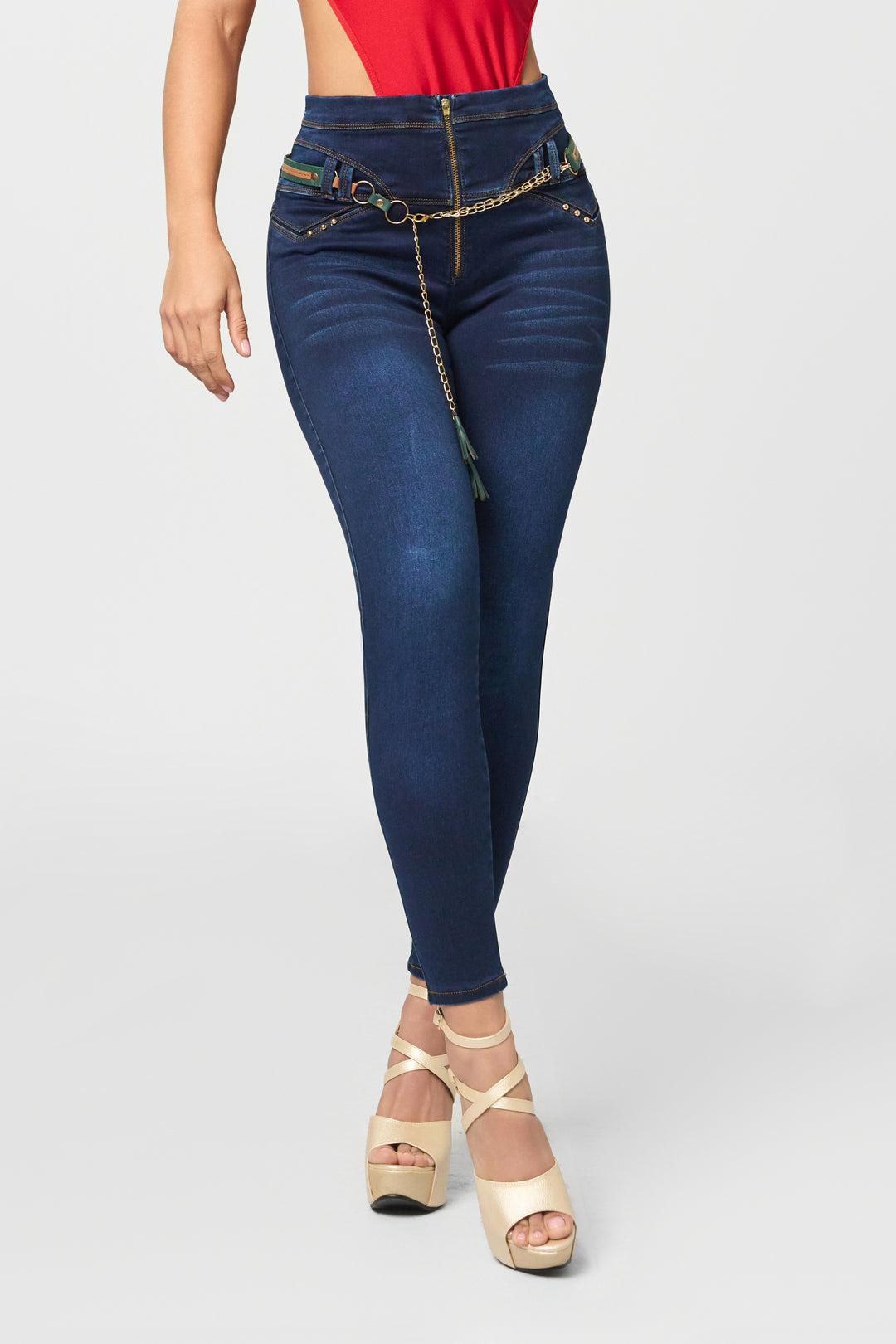 Dark wash skinny jeans color azul, de tiro alto, cadena decorativa y cierre frontal.